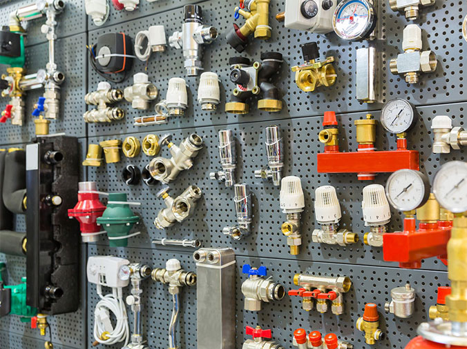 plumbing fittings and connectios on a pegboard in a plumbing supply shop